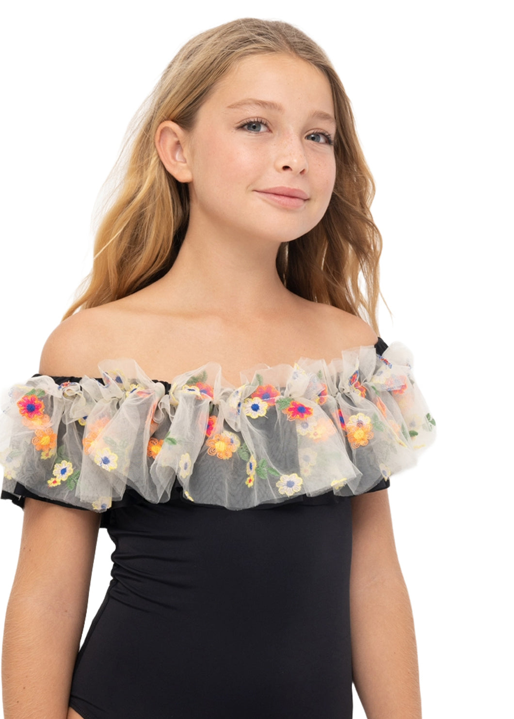 A young girl with blonde hair wearing a black off-the-shoulder swimsuit with a sheer white tulle ruffle collar decorated with colorful embroidered flowers, set against a plain white background.